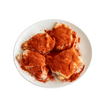 Uncooked chicken thighs seasoned with paprika on a white plate
