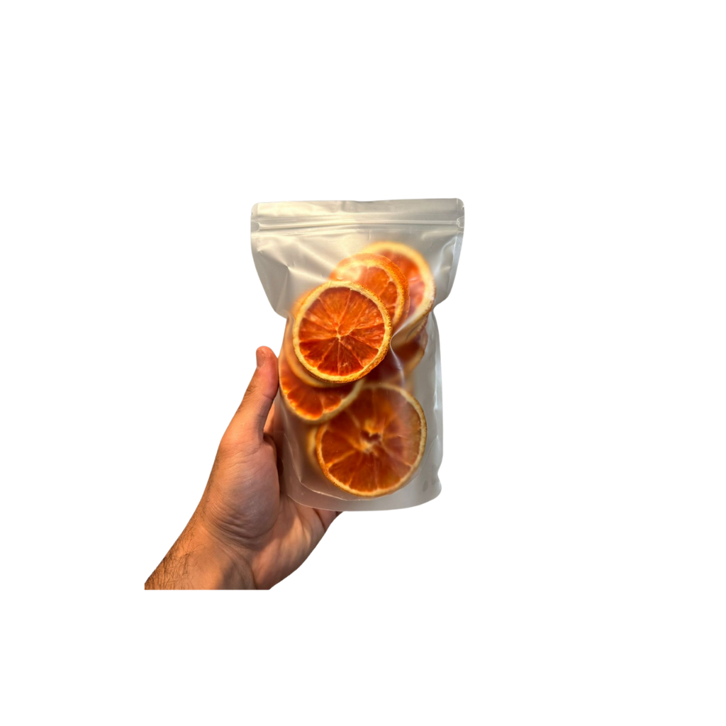 Hand holding a clear bag with dried orange slices against a white background