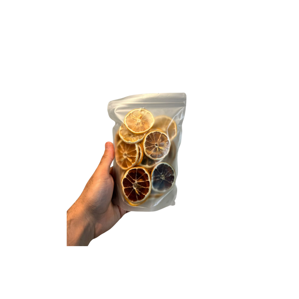 Hand holding a clear plastic bag with dried citrus slices against a white background