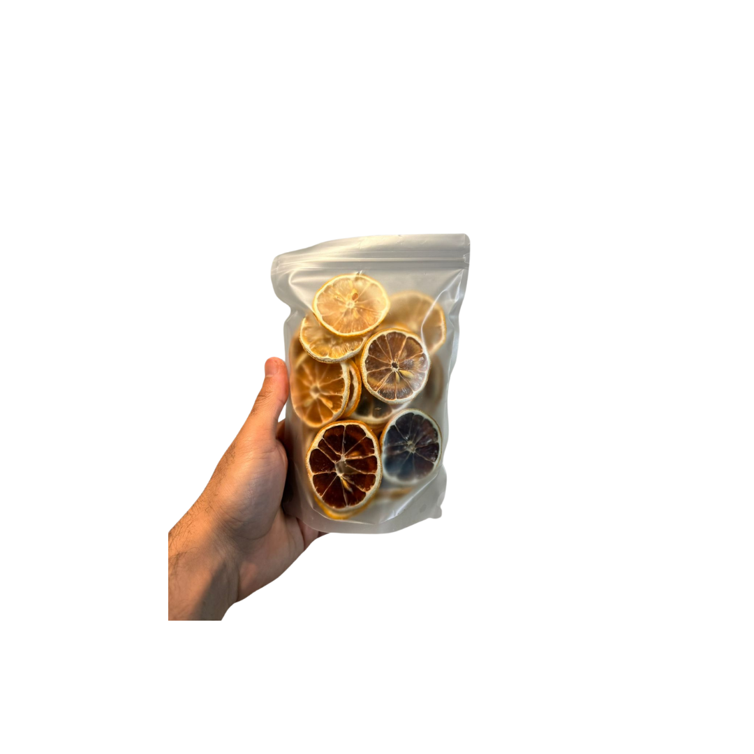 Hand holding a clear plastic bag with dried citrus slices against a white background